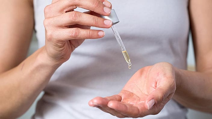 Woman dropping oil on her hand